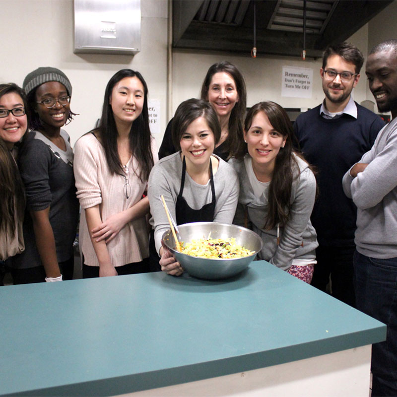 A group of people around a mixing bowl in an industrial kitchen